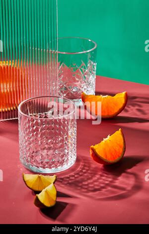 Two empty glass glasses on colored backgrounds with shadows from sunlight Stock Photo