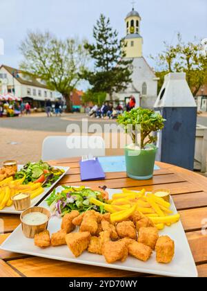 Two perfectly crispy plates of fish and chips, expertly presented on a rustic wooden table in Texel, Netherlands Stock Photo