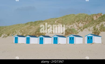 A colorful row of beach huts standing proudly on a sandy beach in Texel, Netherlands, basking in the suns glow Stock Photo