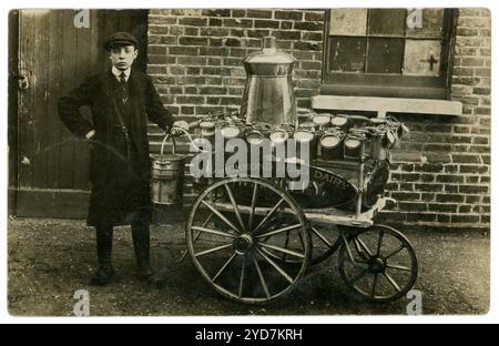 Original WW1 era postcard of young lad who is a street vendor, with his handcart selling milk, door to door. Written on his cart is the name of the proprietor, R Morley who was based at 86, Richmond Road with other dairy shop premises in the Richmond Rd area. R. Morley was a dairy farmer. On the front of this handcart is written 'Cows kept at Couchmore Farm, Esher'. The milk could be refilled into householder's containers. Circa 1913. Stock Photo