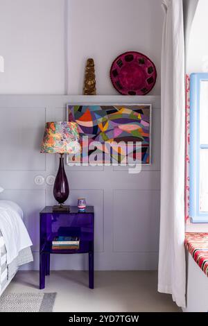 Lamp on purple bedside table with modern art in historic house on the Island of Tinos in Greece Stock Photo