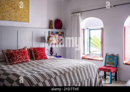 Embroidered red cushions and arched windows in bedroom of historic house on the Island of Tinos in Greece Stock Photo