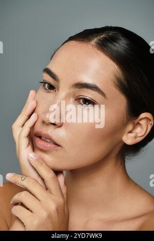 A lovely woman gazes softly, her hand gently touching her face in a serene moment. Stock Photo