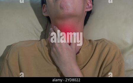 Close up ill young man touching sore throat feeling or dehydration with unhappy. suffering from throat disorder, tonsillitis, allergy, cold concept. Stock Photo
