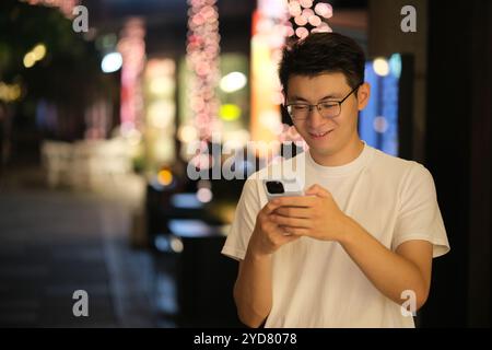 Asian young man text messaging on phone at night Stock Photo
