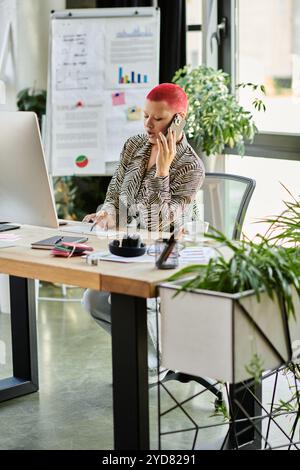 This creative professional communicates thoughtfully on the phone while working at her desk. Stock Photo