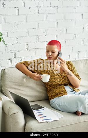 The woman relaxes on the sofa, sipping coffee and engaged in a phone conversation. Stock Photo