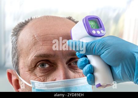 Taking a man's temperature with a digital thermometer. Stock Photo