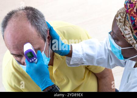 Taking a man's temperature with a digital thermometer. Stock Photo