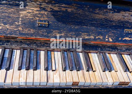 A Close-Up View of Piano Keys with Peeling Paint on a Black Wooden Background in Various Colors Stock Photo