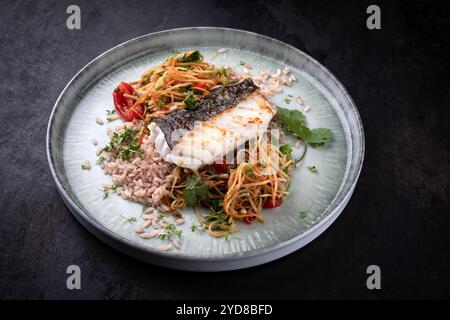 Fried skrei cod fish filet with papaya som tam salad and red rice served as close-up on Nordic design plate with copy space Stock Photo