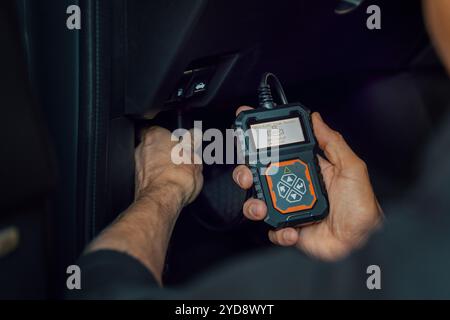 car mechanic using OBD2 scanner, code reader tool to check engine errors and for diagnostics Stock Photo