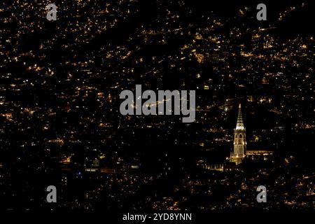 A church stands out among the city lights in one of the many poorer mountain barrios of Medellin, Colombia Stock Photo