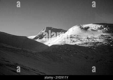A skier's paradise: a breathtaking view of a snow-covered mountain range. A pristine snow-covered slope under a vibrant sky Stock Photo