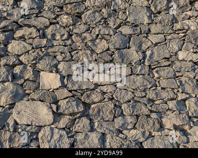 Background of a stacked stone wall made of volcanic rocks of different sizes Stock Photo