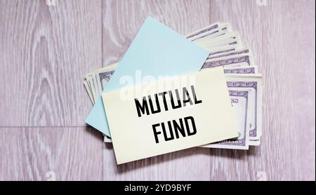 The word Mutual Fund on the sticker and dollars on a gray background. Financial concept. Stock Photo