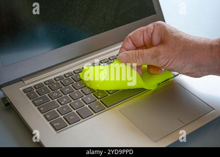 Soft yellow absorbing gel or compound, used on a laptop keyboard to remove dirt, dust, germs and bacteria, hygiene for a healthy office workplace, cop Stock Photo