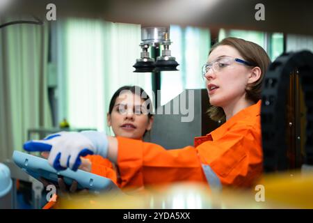 In an electronic parts facility, two female engineers In the plant, inspecting and testing robotic hands used in the production Stock Photo