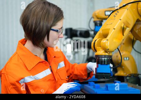 In an electronic parts facility, Female engineers In the plant, inspecting and testing robotic hands used in the production of e Stock Photo