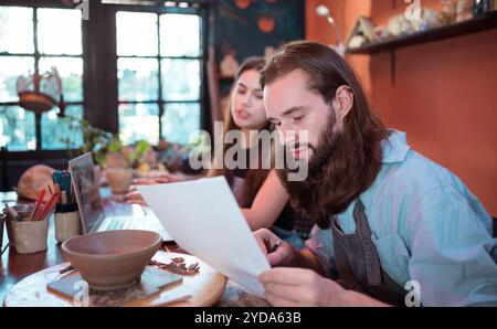 Two young entrepreneurs who own a pottery business. We are discussing the container that the customer wants to be molded. to be Stock Photo