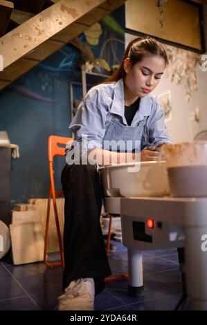 Pottery artist, Young female making a piece of clay molding calmly and meticulously In order to produce the most attractive work Stock Photo