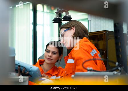 In an electronic parts facility, two female engineers In the plant, inspecting and testing robotic hands used in the production Stock Photo