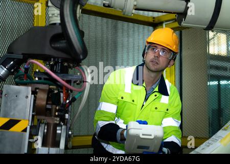 A big welding robot is being inspected and controlled by a robotics engineer. After the machine has been used for the specified Stock Photo