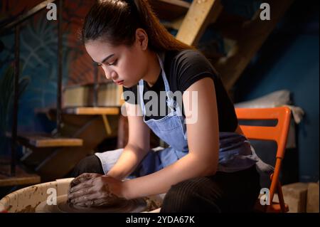 Pottery artist, Young female making a piece of clay molding calmly and meticulously In order to produce the most attractive work Stock Photo