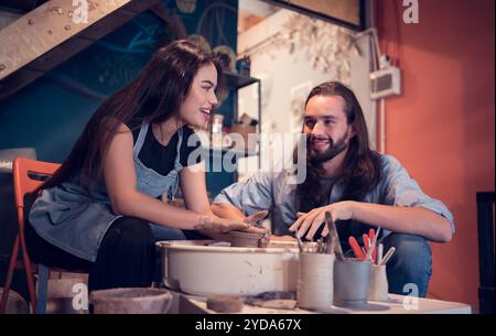 Young couples that enjoy making clay sculptures. Using pottery and assisting one another to create flower vases out of clay Stock Photo