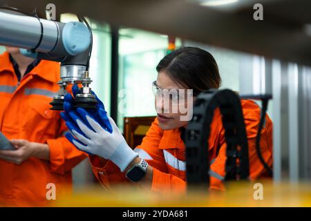 In an electronic parts facility, two female engineers In the plant, inspecting and testing robotic hands used in the production Stock Photo