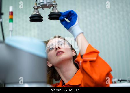 In an electronic parts facility, Female engineers In the plant, inspecting and testing robotic hands used in the production of e Stock Photo