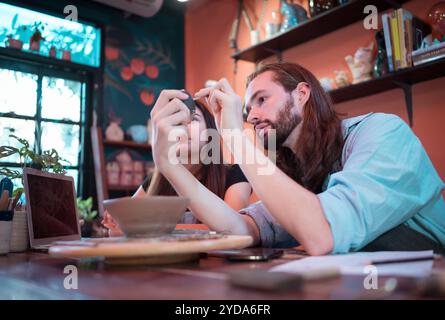 Two young entrepreneurs who own a pottery business. We are discussing the container that the customer wants to be molded. to be used to decorate the h Stock Photo