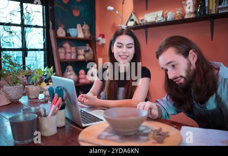 Two young entrepreneurs who own a pottery business. We are discussing the container that the customer wants to be molded. to be Stock Photo