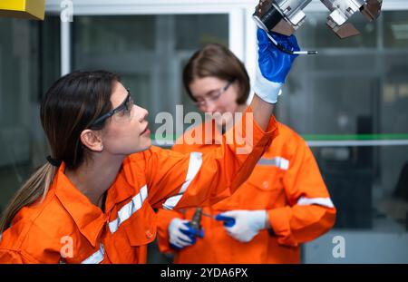 In an electronic parts facility, two female engineers In the plant, inspecting and testing robotic hands used in the production Stock Photo