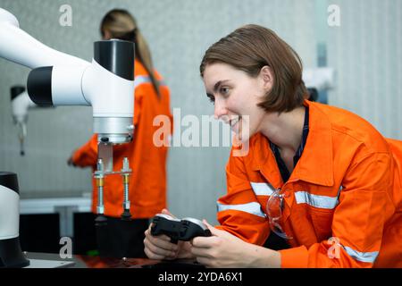 In an electronic parts facility, two female engineers In the plant, inspecting and testing robotic hands used in the production Stock Photo