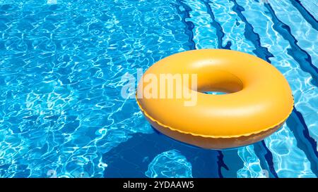 Inflatable ring in swimming pool. Vacation and rest concept. Floating yellow ring on blue water Stock Photo