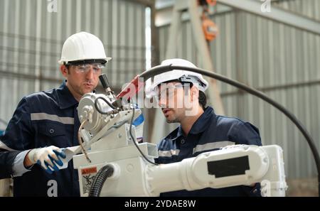 The two engineers check the operation of welding robots. Stock Photo