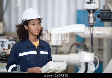 A young female worker is controlling a mechanical robot. Stock Photo