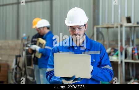 Group of engineers are manipulating a welding robot hand. By combining welding manipulation with a control panel Stock Photo