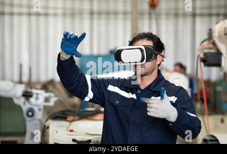 A young male engineer uses a VR machine to operate a welding robot. for precision welding control Stock Photo