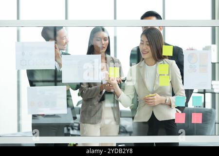 Young entrepreneurs in Asia Organize meetings to brainstorm and review information on glass board Stock Photo