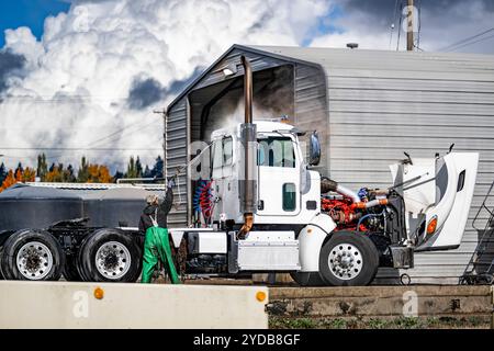 Professional washers wash a commercial big rig gray semi truck tractor ...