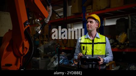 A male worker is controlling a welding robot. by using forcing welding with a control screen which is used for precision welding Stock Photo