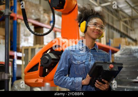 A young female worker is controlling a mechanical robot. to sort out the items that come into the warehouse to wait for the next Stock Photo