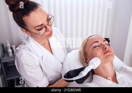 Closeup of face of beautiful relaxing girl undergoing hardware cosmetology procedure in sp Stock Photo