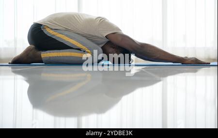Young African man doing yoga exercise in the living room of his homewith the pleasure of relaxing with light sports In the morni Stock Photo