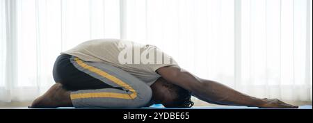 Young African man doing yoga exercise in the living room of his homewith the pleasure of relaxing with light sports In the morni Stock Photo