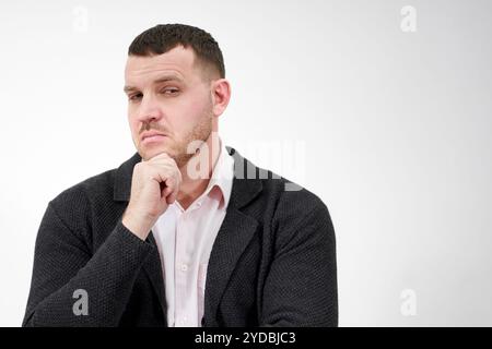 Handsome young pensive man standing against gray background with copy space Stock Photo