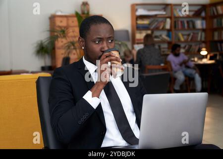 African american businessman with coffee working on laptop in a hotel Stock Photo