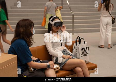 A woman tries the Apple Vision Pro with the help of an assistant at the Apple Jing'an Store in Shanghai, China, on Saturday, August 3, 2024. Stock Photo
